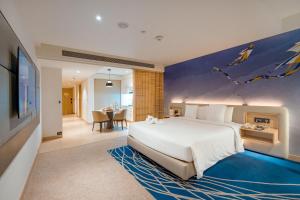 a bedroom with a large bed with a painting on the wall at Novotel Ahmedabad in Ahmedabad