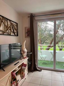 a living room with a tv and a sliding glass door at L'Eucalyptus in Marans