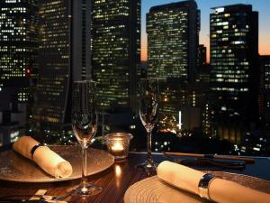 a table with wine glasses and a view of the city at Shinjuku Prince Hotel in Tokyo
