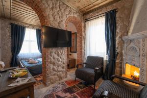a living room with a tv on a brick wall at Alin Stone House in Uçhisar
