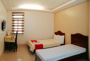 a small room with two beds and a desk at RedDoorz @ Capitol View MC Inn Nueva Vizacaya in Bayombong