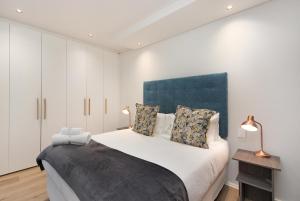 a bedroom with a large bed with a blue headboard at The Cosmo Luxury Suites by Totalstay in Cape Town