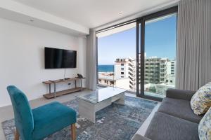 a living room with a couch and a tv at The Cosmo Luxury Suites by Totalstay in Cape Town