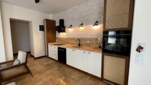 una cocina con armarios blancos y electrodomésticos negros en İskelem Otel, en Akyaka