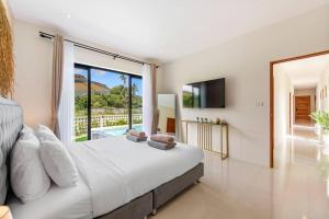 ein Schlafzimmer mit einem großen Bett und einem großen Fenster in der Unterkunft Private Pool Paradise: Sereniwoods 3br in Nathon Bay