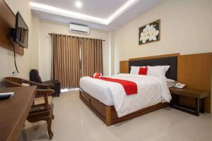 a bedroom with a bed and a desk and a television at RedDoorz Premium @ Jalan Cengkeh Malang in Malang