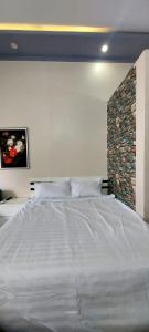a large white bed in a bedroom with a stone wall at SKY HOMESTAY in Buon Ma Thuot