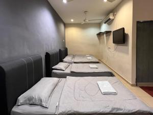 4 camas seguidas en una habitación en Pekan Budget Hotel, en Pekan