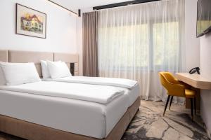 Pokój hotelowy z łóżkiem, biurkiem i oknem w obiekcie Alexandrion Experience w mieście Sinaia