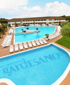 a large swimming pool with chairs and a hotel at Hotel Centro Turistico Gardesano in Bussolengo