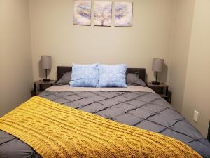 a bedroom with a bed with a yellow blanket and two lamps at Ridgeland Retreat/ Street level Apt easy access in Berwyn