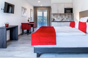a bedroom with a large white bed with red pillows at Motel-Résidence Ô Pied à Terre in Montilliez