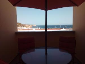 a table with an umbrella in front of a window at Casa Yucca in Salema