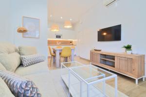 a living room with a couch and a table with a television at iloftmalaga Playa de Huelin in Málaga