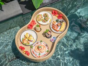 einen Tisch mit Teller mit Speisen auf einem Pool in der Unterkunft Ubud Art Resort in Ubud