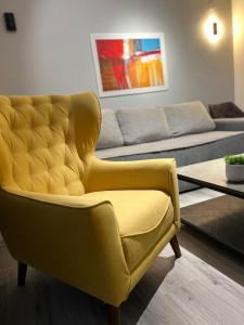 a yellow chair in a living room with a couch at Mavrovo Square " Villas & Apartment " in Mavrovo