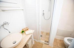 La salle de bains blanche est pourvue d'un lavabo et d'une douche. dans l'établissement Agriturismo "Il Vignale", à Ostuni