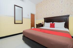 Schlafzimmer mit einem großen Bett und einem roten Kissen in der Unterkunft RedDoorz near Taman Krida Budaya Malang in Malang