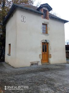 a white building with a brown door and a door istg at Maison calme in Vinzelles