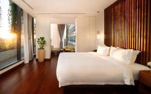 um quarto com uma grande cama branca e uma grande janela em Koulen Central Hotel em Siem Reap