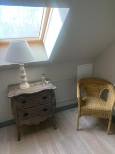 una lámpara en un tocador junto a una silla en un ático en Le Relais, en Arnage