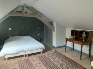 1 dormitorio con cama blanca y mesa de madera en Le Relais, en Arnage