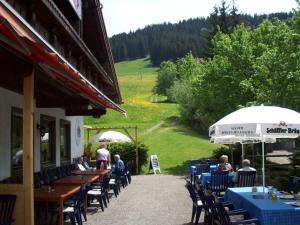 a group of people sitting at a restaurant with tables and umbrellas at Ferienwohnpark Oberallgäu in Missen-Wilhams