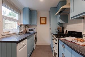 uma cozinha com armários azuis e um fogão em Didi's Cottage em Cowes