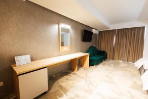 una camera d'albergo con scrivania e sedia verde di Pensiunea Axe Boutique a Galaţi