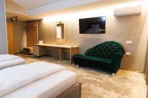 a hotel room with a green chair and a desk at Pensiunea Axe Boutique in Galaţi