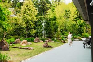 a woman walking down a path in a garden at Hotel Okura Kyoto Okazaki Bettei -Age Requirement 12 over- in Kyoto
