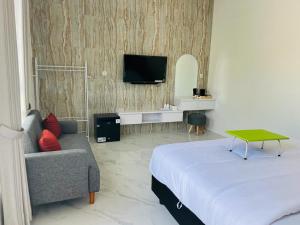 una camera con letto, divano e TV di Urbanview Hotel Nimara Ngawi by RedDoorz a Ngawi Altre 22 foto