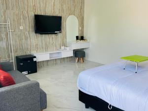 una camera da letto con un letto, una TV e un divano di Urbanview Hotel Nimara Ngawi by RedDoorz a Ngawi