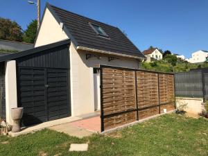 un garage avec un toit noir et une clôture dans l'établissement Jolie maisonnette, à Auxerre