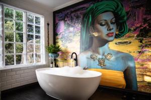 a bathroom with a tub and a painting of a woman at Mettahouse Cape Town in Cape Town +61 photos