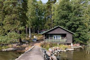 a small cabin next to a river with trees at Villa Merituuli - Charming Seafront Cottage in Porvoo