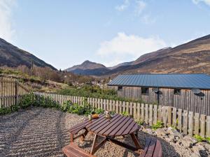 a wooden table and bench in front of a fence at 1 Bed in Kinlochleven 87131 in Kinlochleven