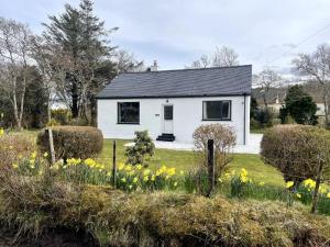 a white house in a field of flowers at 2 Bed in Camus Croise 86437 in Isleornsay