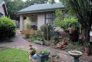 a house with a bunch of plants in the yard at Stop-a-While in Krugersdorp