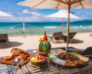 a table with plates of food on the beach at Twinpalms Tented Camp in Bang Tao Beach