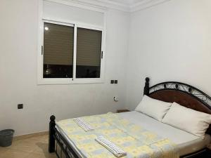 a bedroom with a bed and a window with a keyboard at Bel Appartement à Proximité de la Gare Routière in Agadir
