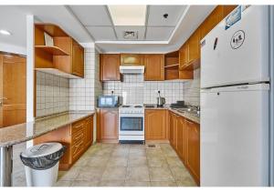 uma cozinha com armários de madeira e um frigorífico branco em Amazing 3BR Apartment next to Emirates Towers Metro in DIFC em Dubai