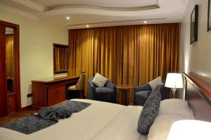 um quarto de hotel com uma cama e cadeiras e uma secretária em Crown Tower Hotel em Al Jubail