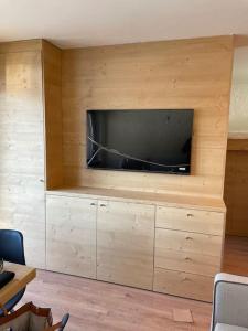 sala de estar con TV de pantalla plana en una pared de madera en Grazioso appartamento a Madonna di Campiglio, en Madonna di Campiglio