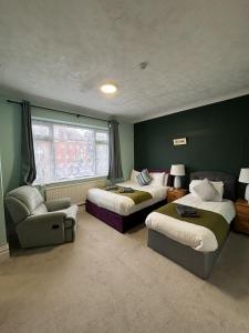 a bedroom with two beds and a couch and a chair at Boscombe Spa Hotel in Bournemouth