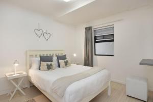 - une chambre blanche avec un grand lit et une fenêtre dans l'établissement Azure 11, à Bloubergstrand