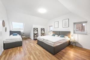 2 camas en un dormitorio con suelo de madera y paredes blancas en Sali Homes - Residenz zum Breitenauer See, en Obersulm