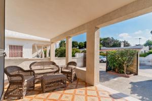 - une terrasse couverte avec des chaises en osier et une table dans l'établissement Villa letizia Baia del sol, à Porto Cesareo