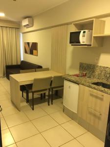 eine Küche und ein Wohnzimmer mit einem Tisch und einer Mikrowelle in der Unterkunft Barretos Thermas Resort in Barretos