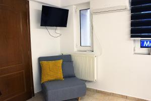 a room with a chair and a tv and a window at FLUMEN HOUSE - Studio Apt - Trikala in Tríkala